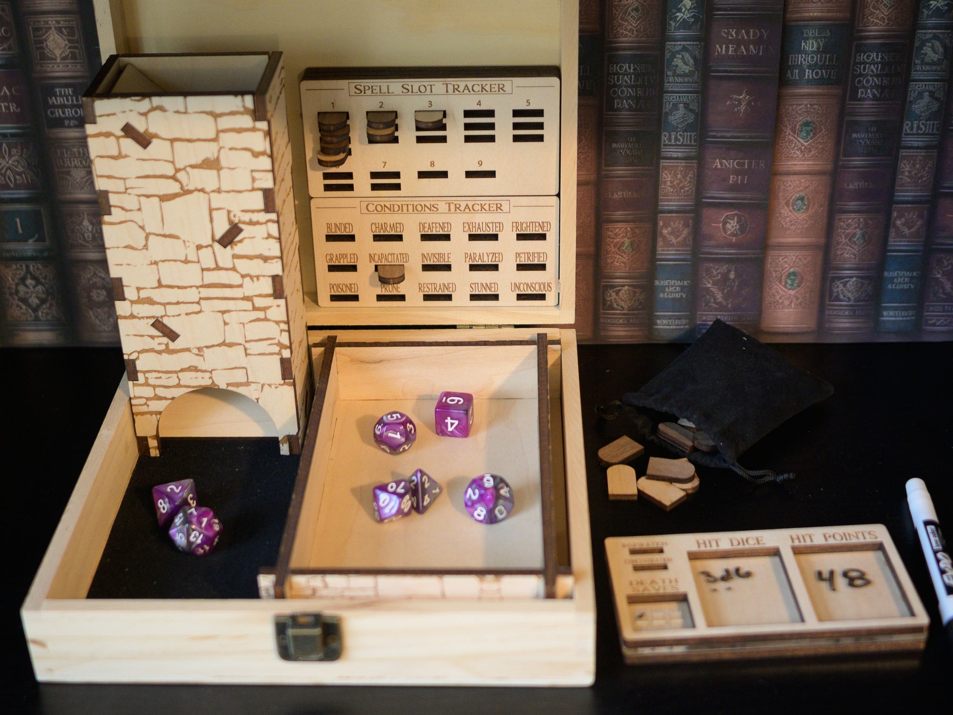 Wooden dice storage box with purple dice and game accessories on a shelf with books in the background.