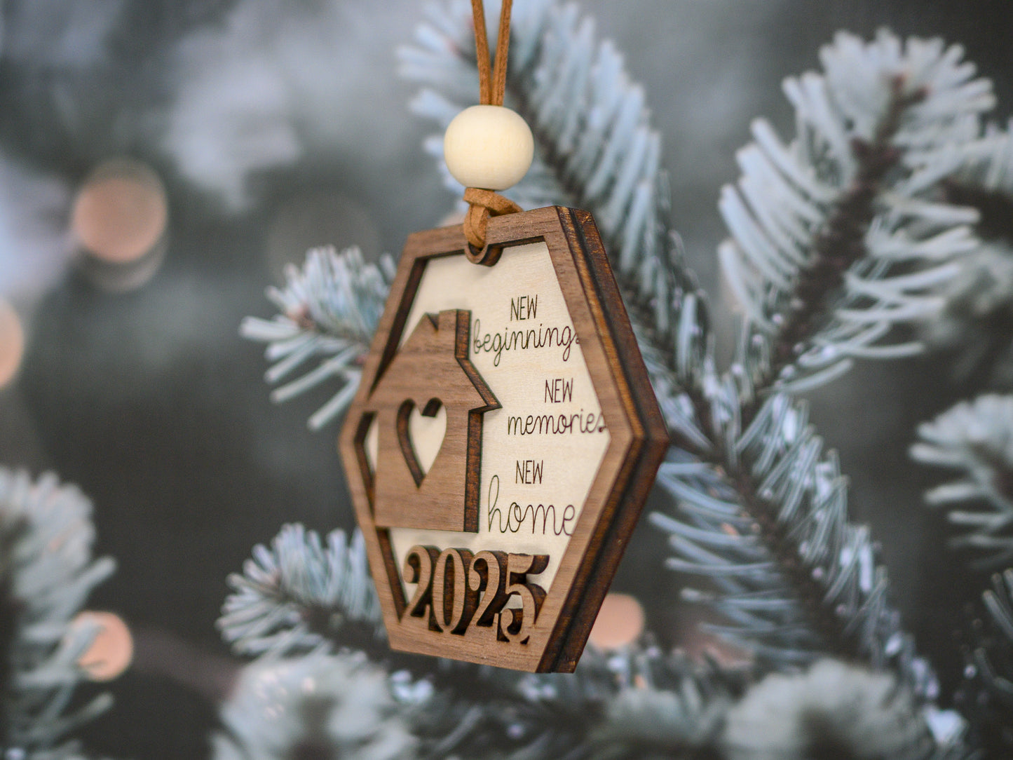 Wooden ornament shaped like a house with text on a Christmas tree branch.